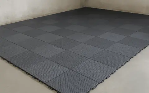 Dalles modulaires grises posées sur un sol de garage. L'épaisseur de la dalle béton garage est ici optimisée par ce revêtement pratique.