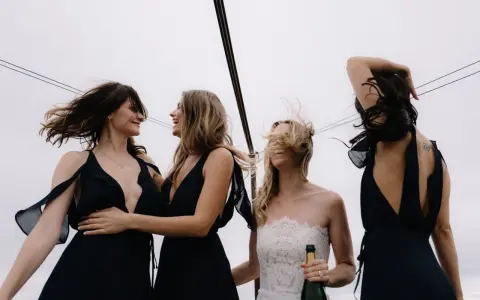 Sorelle della sposa, con abiti neri eleganti, celebrano il matrimonio con champagne. Accessori per abito nero matrimonio perfetti per un look sofisticato.