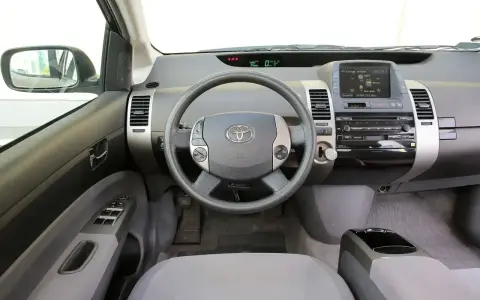Wnętrze Toyoty Prius 2 z kierownicą, panelem radia i ekranem.