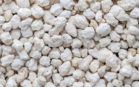 Gros plan sur une texture de perlite exfoliée, de petites roches blanches et poreuses, parfaites pour l'aération du sol.