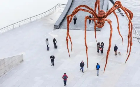 Une immense araignée de bronze, œuvre de Louise Bourgeois, domine une place où quelques passants curieux l'observent.