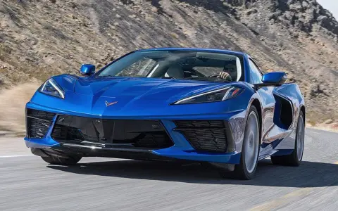 Błękitny Chevrolet Corvette Stingray pędzi po pustynnej drodze.