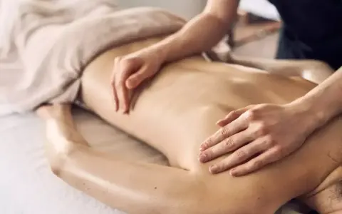Dłonie terapeuty wykonują relaksacyjny masaż pleców, przynosząc ukojenie i odprężenie.