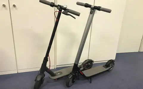Deux trottinettes électriques, noires et grises, prêtes à l'emploi. La trottinette électrique définition : un moyen de transport urbain pratique.
