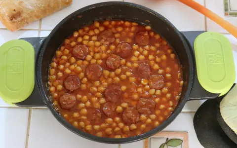 Un plato humeante de garbanzos con chorizo, listo para disfrutar con pan crujiente.