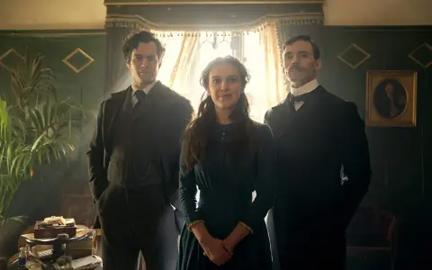 Enola Holmes, con su edad recomendada, posa entre sus hermanos Sherlock y Mycroft.
