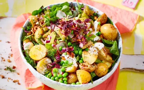 Kartoffelsalat mal anders: Ein bunter Mix aus kleinen Kartoffeln, Erbsen, Radieschen, Zwiebeln und Kräutern in einer Schüssel.