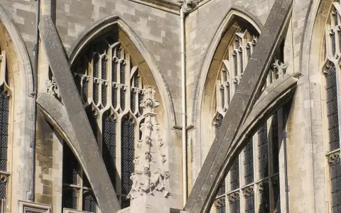 Detalle arquitectónico de una catedral gótica, mostrando la intrincada red de contrafuertes y arbotantes que sostienen sus imponentes muros y ventanas.