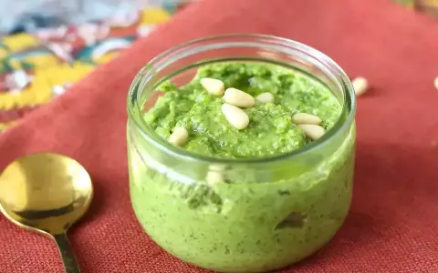 En burk med hemgjord pesto, toppad med pinjenötter. Perfekt för ditt nästa pesto recept!