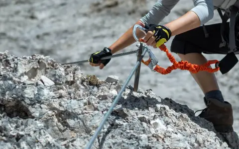 Ręce w rękawiczkach trzymają się stalowej liny na via ferrata. To część ekscytujących szlaków na Słowacji.