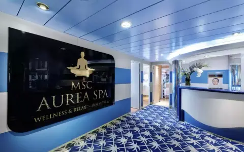 Ingresso della MSC Aurea Spa, con un'insegna dorata su sfondo nero e un tappeto blu con motivi bianchi.