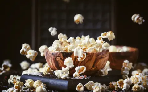 Chrupiący popcorn w drewnianej misce, unoszący się w powietrzu. Czy zastanawiałeś się nad jego indeksem glikemicznym?