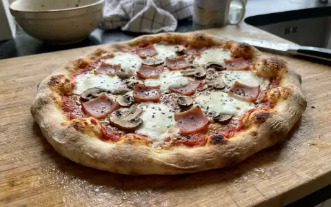 En härlig hemmagjord pizza med skinka och champinjoner, redo att avnjutas.