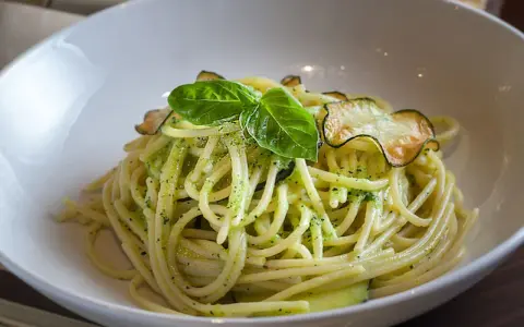 Spaghetti cremosos con calabacín y albahaca en un cuenco blanco.
