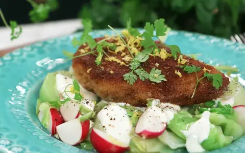 En gyllene kyckling kiev toppas med citronzest och persilja, serverad på en bädd av krispig sallad med rädisor och krämig dressing.