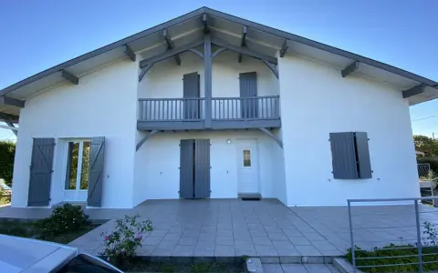 La façade maison 2 couleurs, blanche et grise, présente un balcon avec des volets assortis.