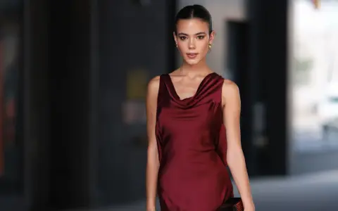Una mujer elegante con un vestido burdeos satinado, ideal para saber como combinar un vestido burdeos para una boda.