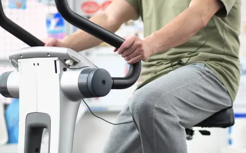 Osoba ćwiczy na rowerku stacjonarnym. Dowiedz się, ile jeździć na rowerku stacjonarnym, aby osiągnąć swoje cele.