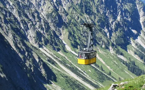 Gelbe Seilbahn schwebt über steile Hänge, ideal für eine Nebelhorn Wanderung.