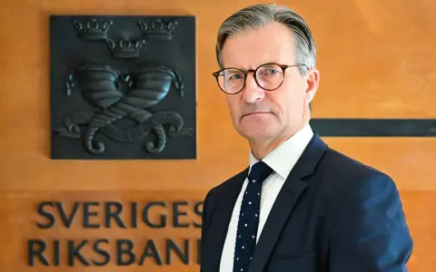 Erik Thedéen, med Riksbankens emblem bakom sig, ser ut som en person som vet hur man hanterar barn och ekonomi.