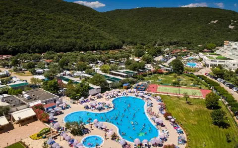 Wakacje na **camping Oliva** to baseny, korty tenisowe i mnóstwo zieleni pod górą.