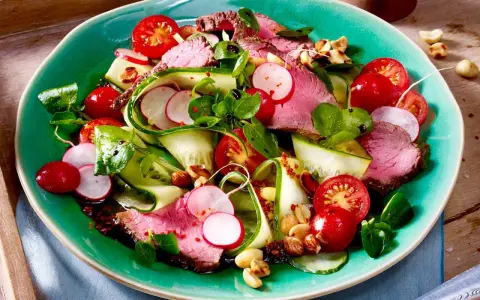 Saftiger Rinderbraten auf einem bunten low carb salat mit Gurke, Radieschen und Kirschtomaten. Nüsse sorgen für Crunch.