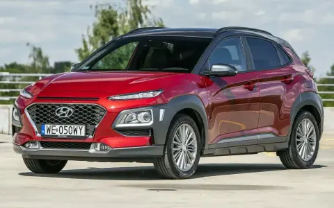 Czerwony, mały SUV Hyundai Kona z czarnym dachem, zaparkowany na zewnątrz.