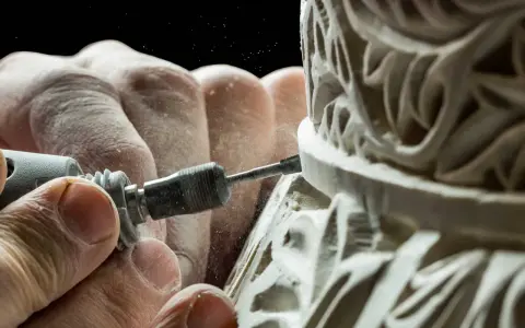 Mains habiles sculptant un ornement complexe, poussière fine dans l'air. Une image capturant la précision de la formation artisanat d'art.