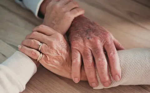 Mains âgées se tenant, symbolisant le soutien et l'amour, même face à un conjoint narcissique.