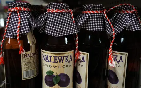 Butelki nalewki lwóweckiej z etykietami i ozdobnymi sznurkami.