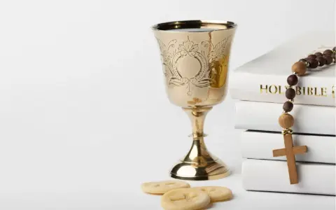 Złoty kielich, hostie, różaniec i Biblia. Symbolika sakramentu, który może być odnotowany w akcie chrztu.