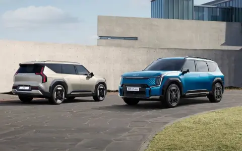 Dwa samochody elektryczne Kia EV9 w kolorach niebieskim i jasnoszarym stoją na zewnątrz.
