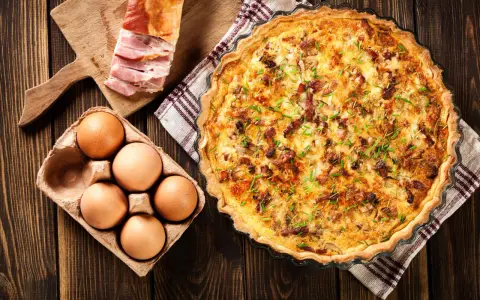 Quiche Lorraine, un classique de la gastronomie lorraine, avec ses ingrédients frais : œufs, lardons et herbes.