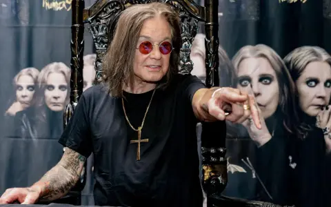 Ozzy Osbourne, geboren 1948, sitzt auf einem Thron und zeigt mit dem Finger. Im Hintergrund sind Bilder von ihm zu sehen.