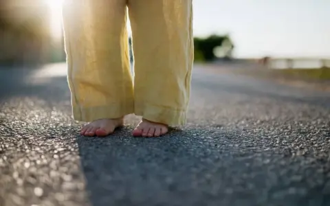 Barfuß auf Asphalt, die weite Leinenhose im Abendlicht. Ein Gefühl von Freiheit, als ob die Hose frisch gewaschen wäre und bereit für neue Abenteuer.