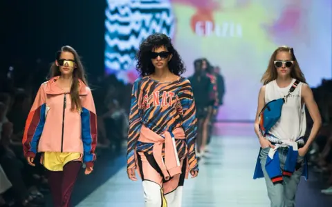 Modelki na wybiegu prezentują stylizacje, które idealnie sprawdzą się, jak się ubrać na imprezę w stylu lat 90. Kolorowe bluzy, dresy i neonowe dodatki.