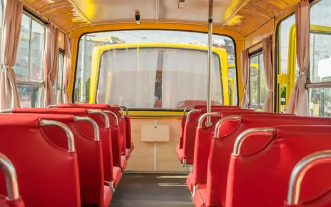 Wnętrze żółtego autobusu z czerwonymi siedzeniami, widok od tyłu.