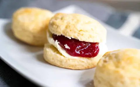 Frisch gebackene Scones mit Clotted Cream und Erdbeermarmelade, ein köstliches Rezept für den Nachmittagstee.