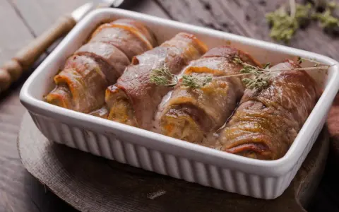 Roladki ze schabu po cygańsku, zawinięte w boczek, pieczone w sosie śmietanowym, ozdobione gałązkami tymianku.