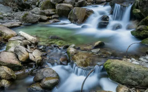 Acqua cristallina scorre tra rocce muschiose, creando un effetto seta su un ruscello di montagna.