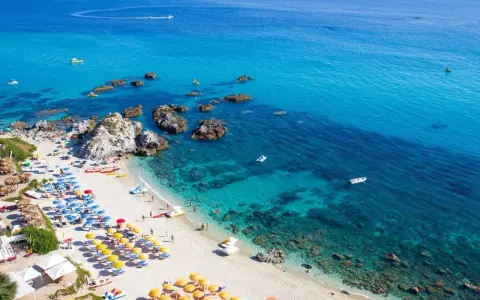 Spiaggia calabrese con ombrelloni colorati e mare cristallino, ideale tra i posti da visitare in Calabria con bambini per una vacanza indimenticabile.