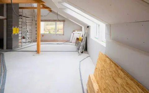Przebudowa poddasza na pokoje. Widoczna dobudowa do domu w trakcie prac, materiały budowlane, rusztowania i instalacje.