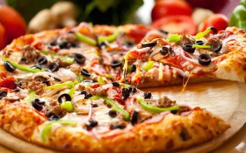 Gotowe ciasto na pizzę z mnóstwem dodatków: pepperoni, oliwki, papryka, cebula i ser. Idealne na wieczór filmowy!