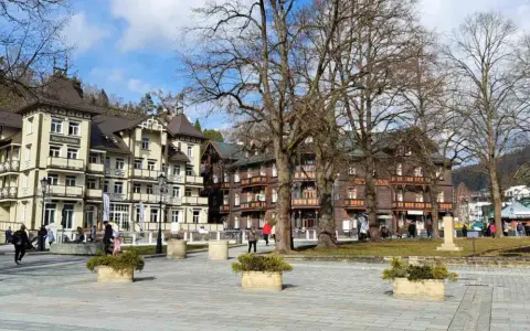 Spacerowicze na rynku w Krynicy-Zdroju, otoczonym zabytkową architekturą.