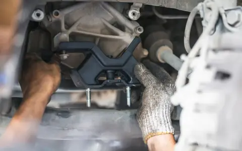 Mechanic installing a new engine mount. This repair is essential for smooth driving and can impact motor mount replacement cost.