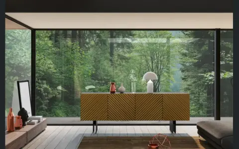 Madia moderna con ante a righe diagonali, un tavolino basso con oggetti decorativi e una grande vetrata su una foresta lussureggiante.