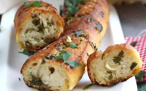 Pan de ajo recién horneado, dorado y crujiente, con trozos de perejil y ajo visibles en su interior.