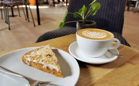 Ein Stück Kuchen mit Nüssen und eine Latte Art im **Kuchen Cafe**.