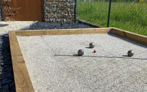 Terrain de pétanque avec boules et cochonnet sur du gravier fin. Le choix du quel sable pour terrain de pétanque est crucial pour un jeu parfait.