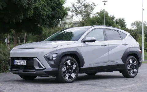 Szary Hyundai Kona Hybrid stoi na zewnątrz, z widocznym przodem i bokiem.